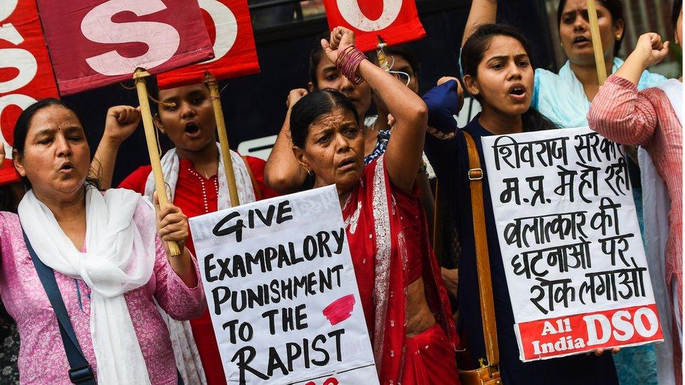 Women protest the rape of an eight-year-old holding sign that says 'give examploary punishment to the rapist'