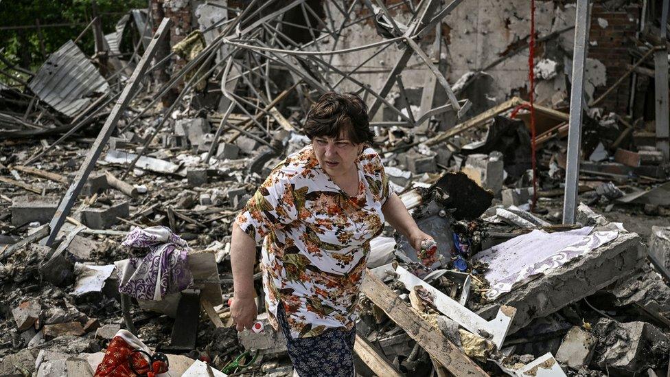 A woman looks for her belongings in the rubble of her house in Sloviansk, Ukraine