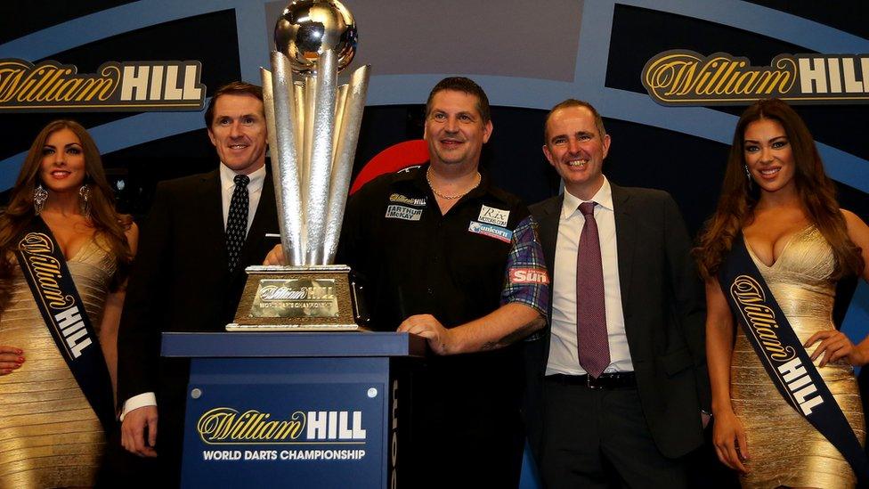 Scotland's Gary Anderson poses with A.P McCoy (second left) after defeating Phil Taylor of England in the final of the 2015 William Hill PDC World Darts Championships at Alexandra Palace 2015 in London