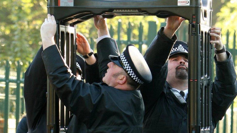 Police officers erect a metal detector arch at a school in Leyton, in east London, in 2009