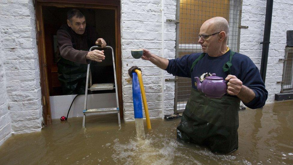 Men drinking tea in flooded property