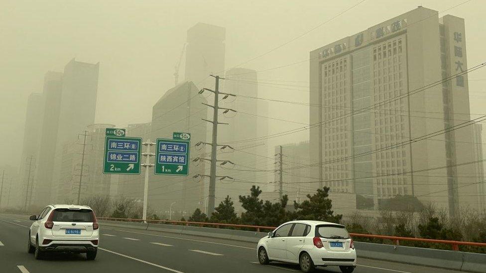 Cars on empty road, sandy haze