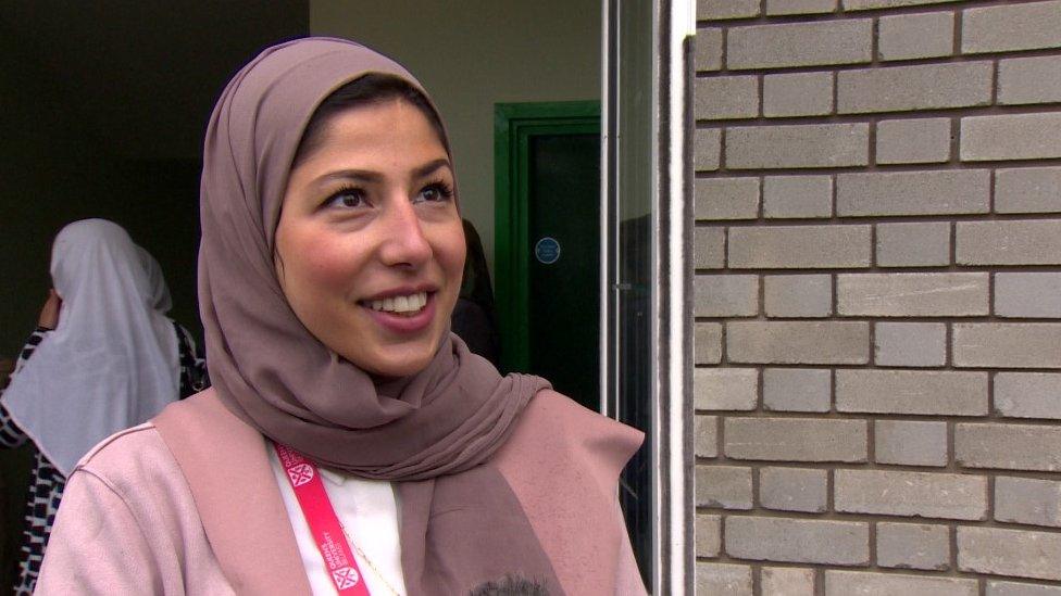 Haneen smiles at the camera in front of a door