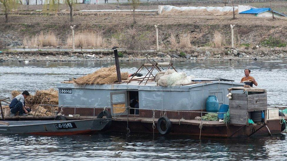 North Koreans on a boat as seen on the Yalu river, Qingcheng