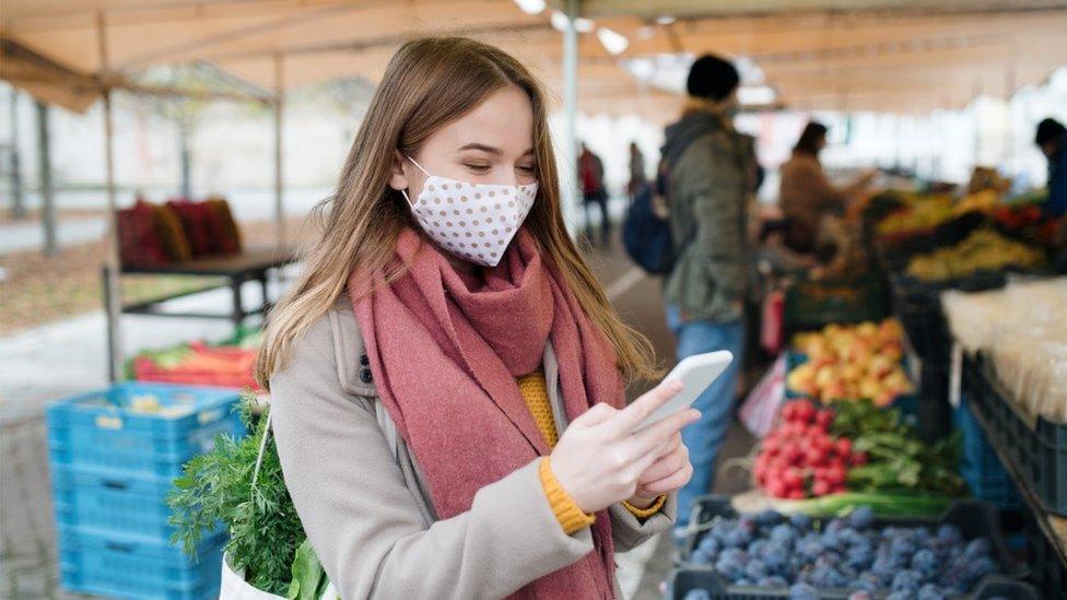 Masked woman buys fruit at a market