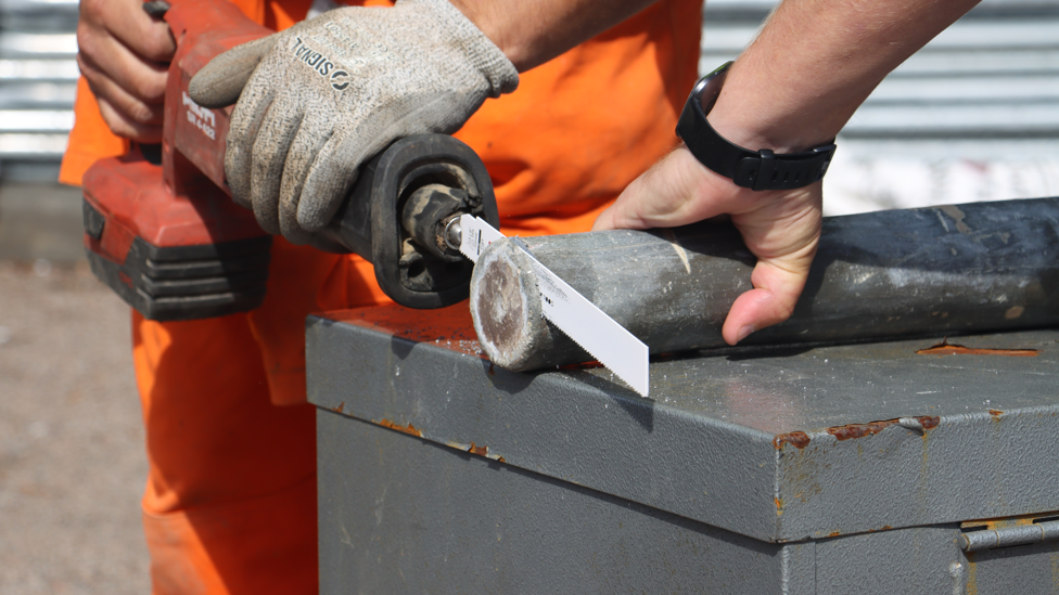 A metal pipe being sawn open