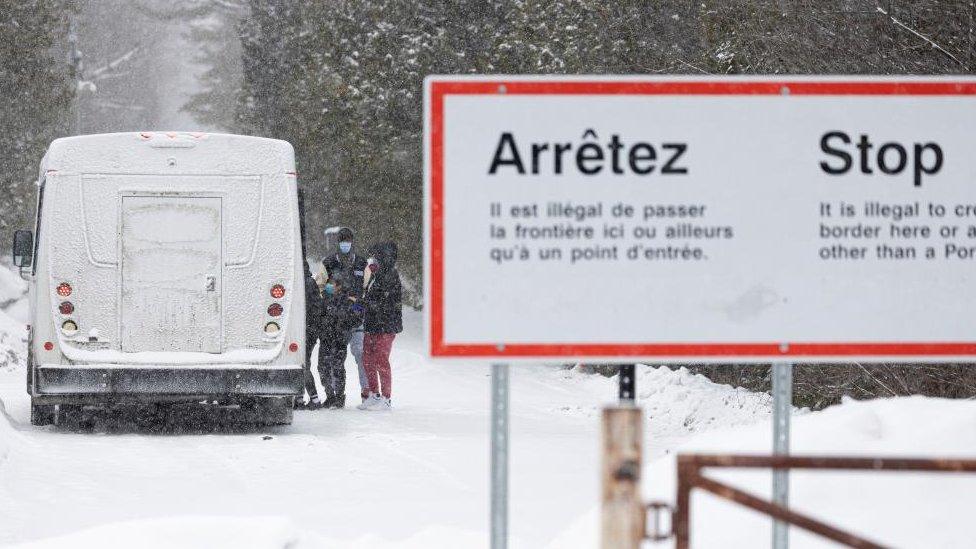 People board a bus near a sign that says crossings are illegal