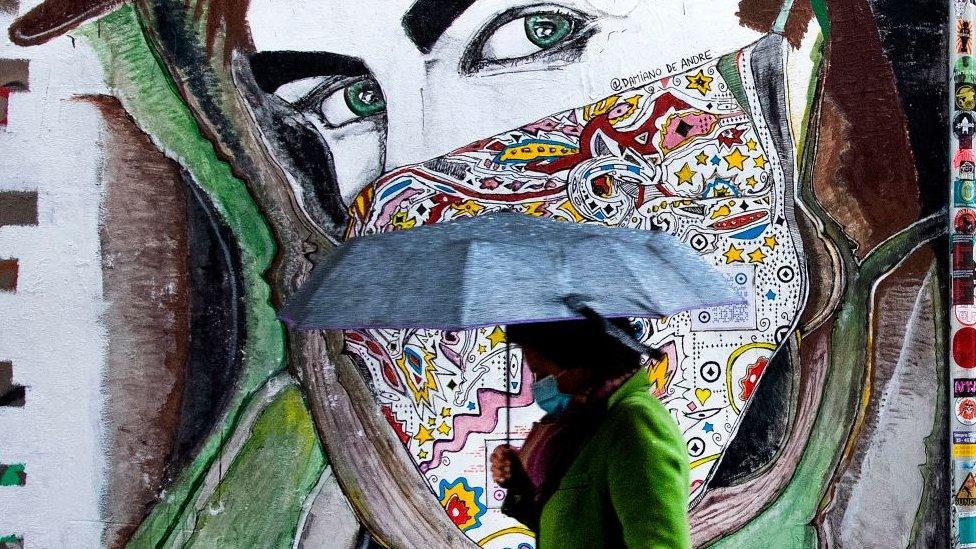 A woman wearing a face mask walks past a mural in Rome's Trastevere district