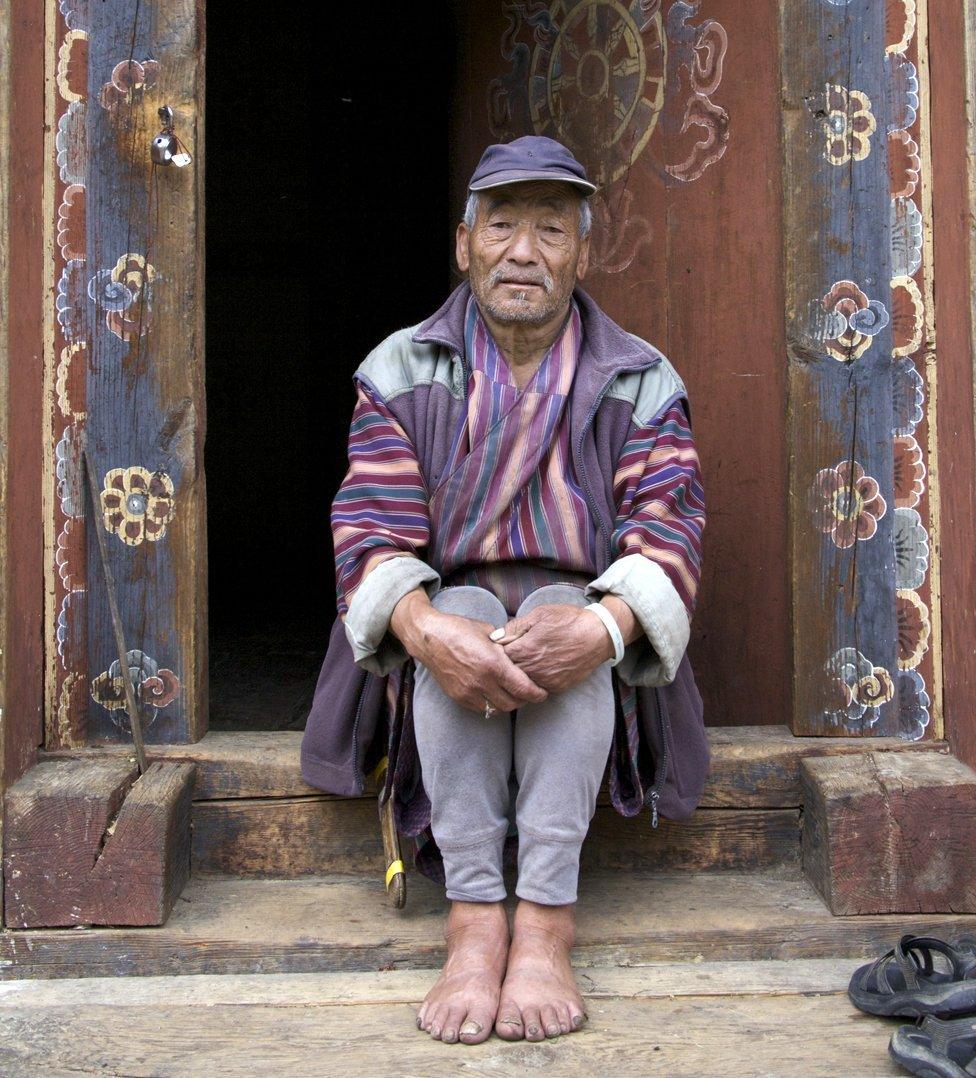 Kama Tschering sits in a traditional wooden doorway