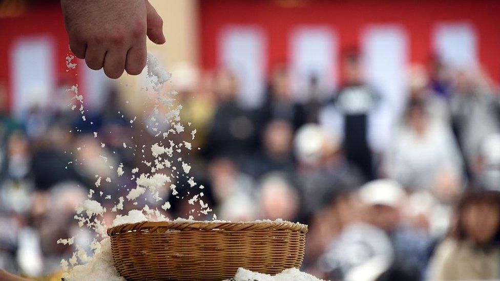 A wrestler grabs a handful of salt from a basket