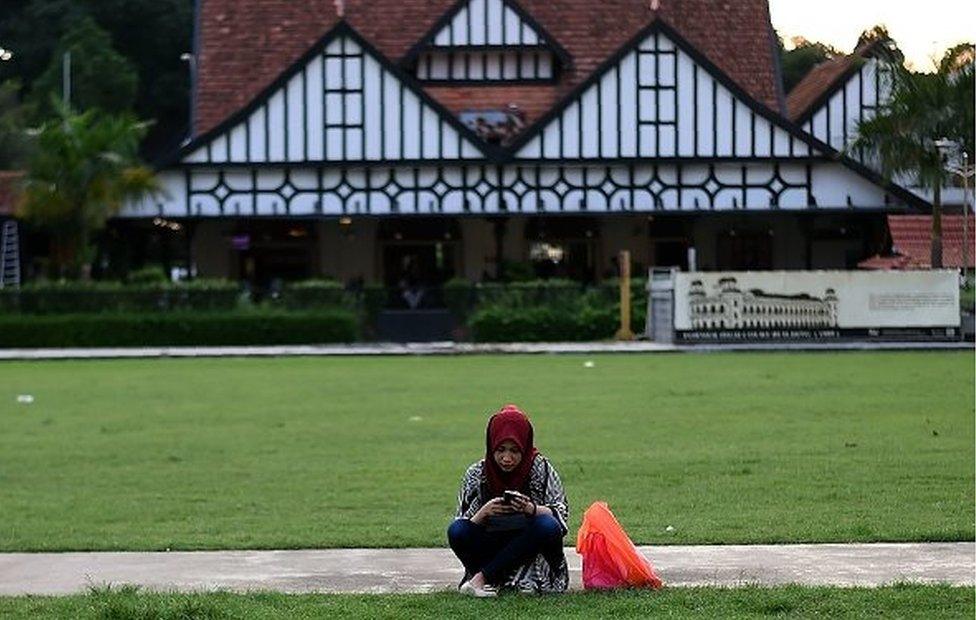 A Malaysian Muslim girl sits in an open field at Independence Square in Kuala Lumpur on June 28, 2017.