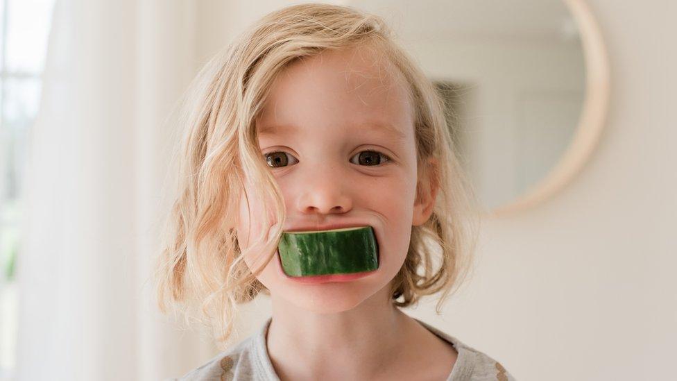 Child with cucumber in mouth.