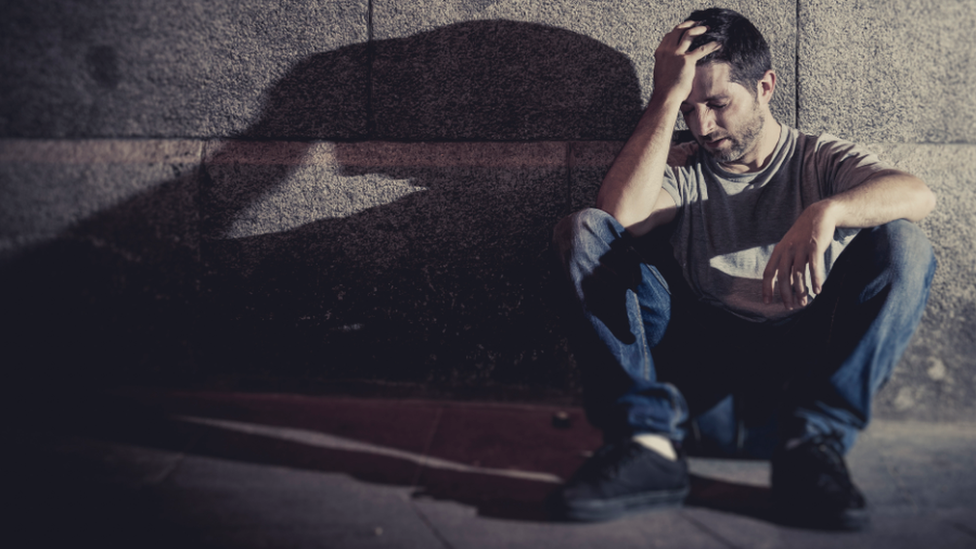 Man sitting alone with hand on head