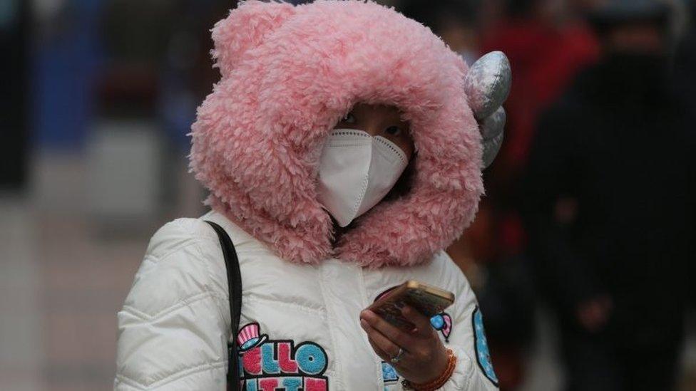 A Chinese woman wearing mask walks in a shopping street during a hazy day in Beijing city, China, 22 December 2015