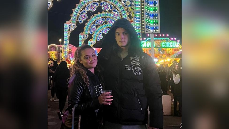 Ben and his girlfriend Tayana at a fair with bright fairy lights