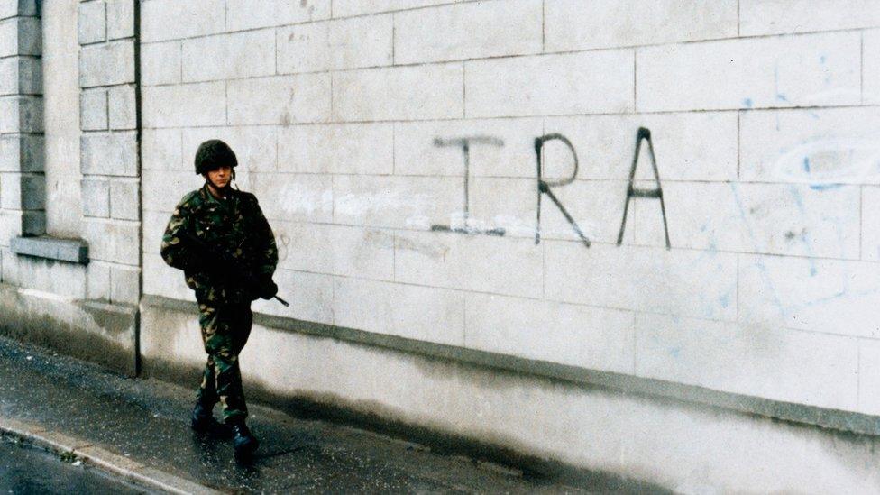 Soldier walking passed IRA graffiti