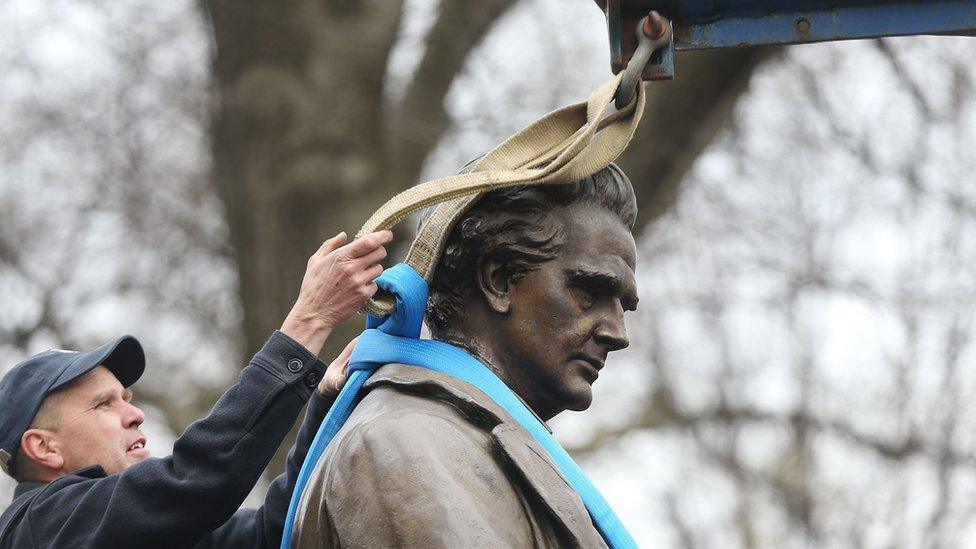 A worker secures the statue of J. Marion Sims before it is driven away, 17 April 2018