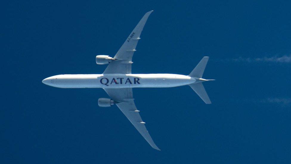 Qatar Airways plane flying overhead.