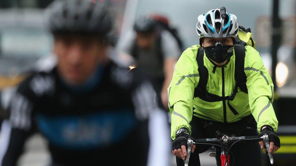 Cyclist wearing smog mask in London traffic