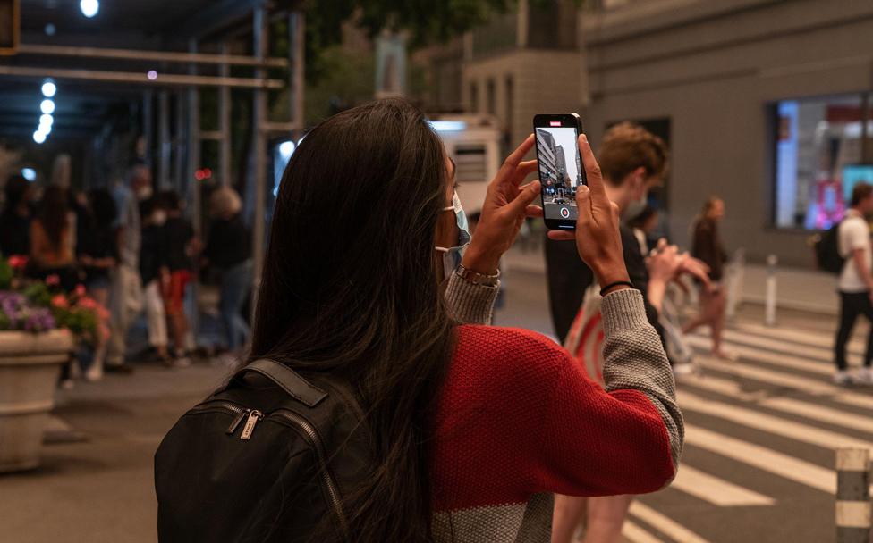 A woman wearing a face mask takes a photo of hazy New York, US, because of bad air quality brought in by smoke of Canadian wildfires on 7 June 2023