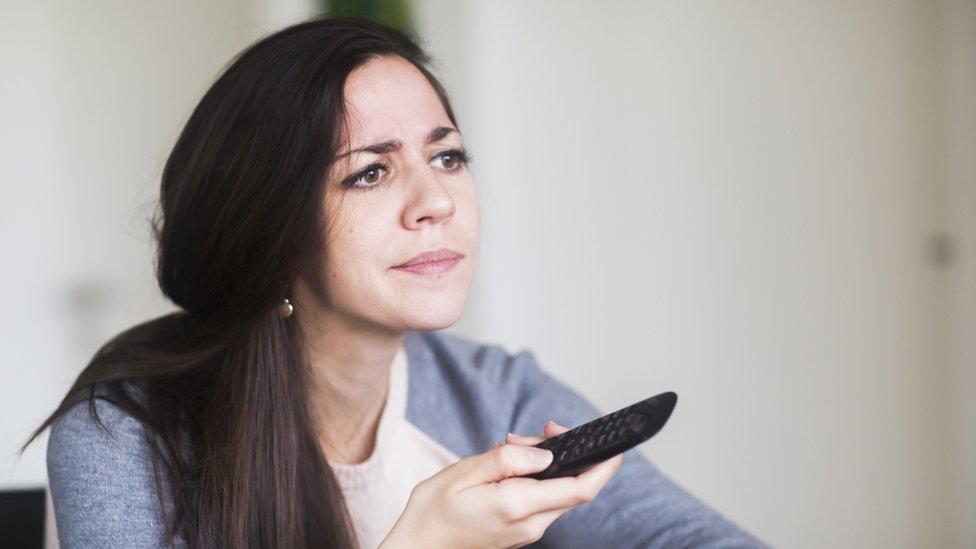 Woman pressing TV remote