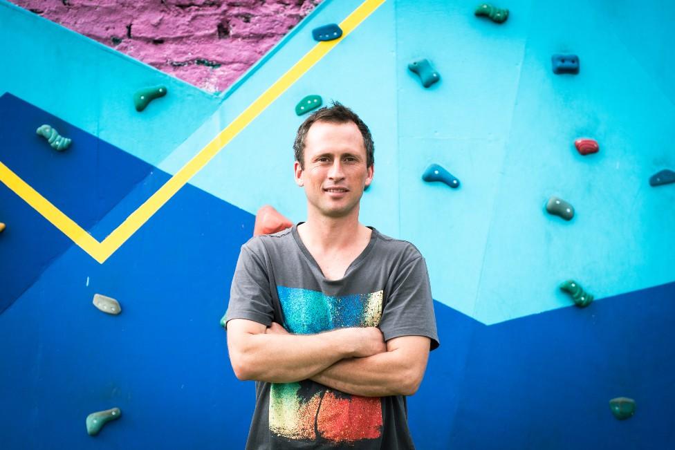 Pedro Anguita stands in front of one of the climbing walls at the community gym