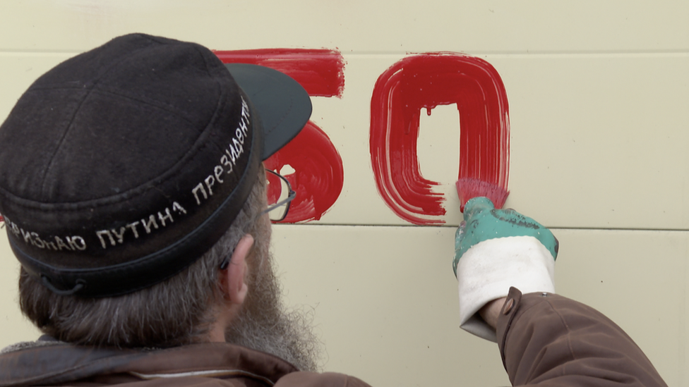 Image shows protester painting wall