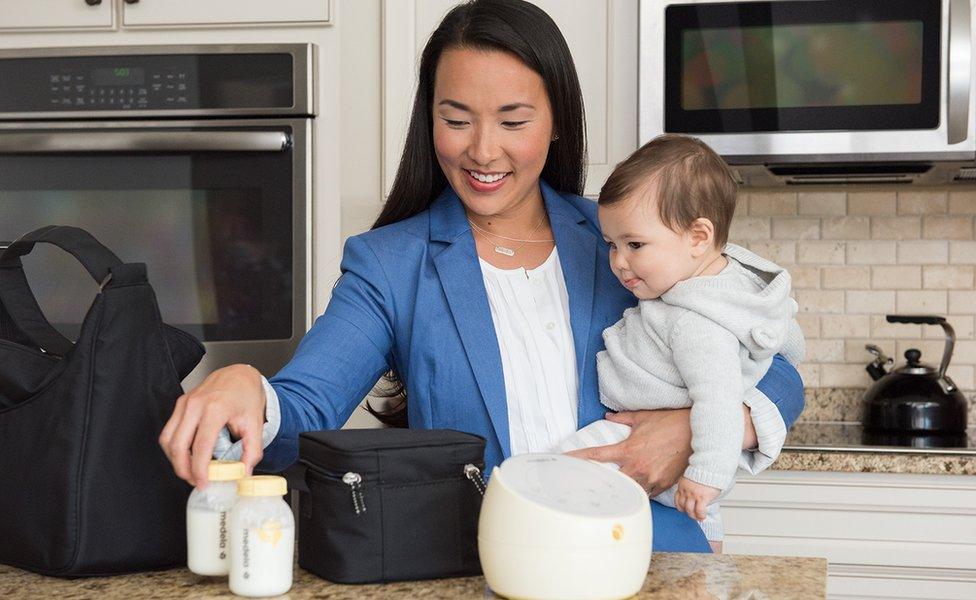 Woman with baby preparing expressed milk bottles