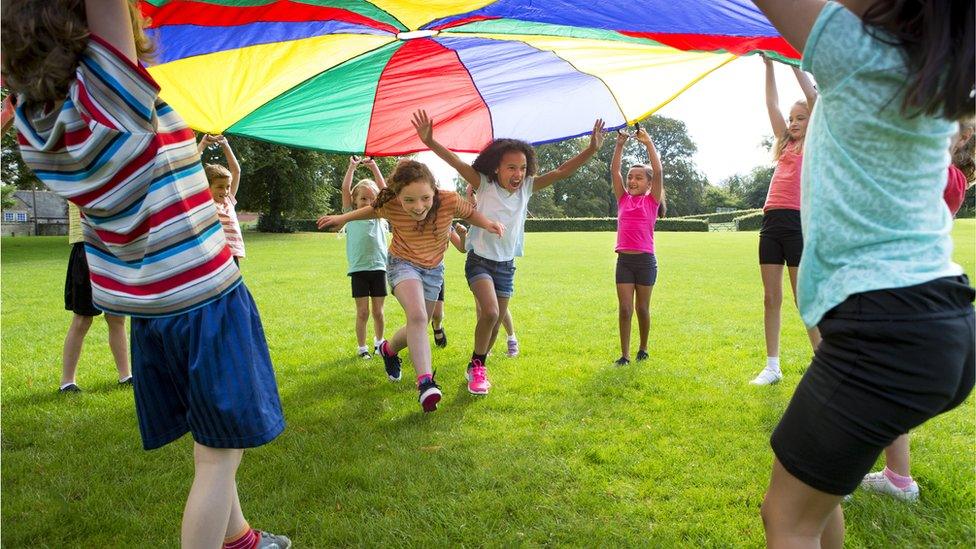 children run under colourful tent