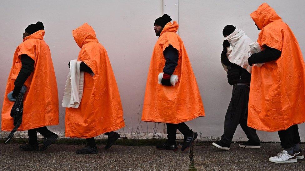 Migrants standing in a queue waiting to be processed in Kent.