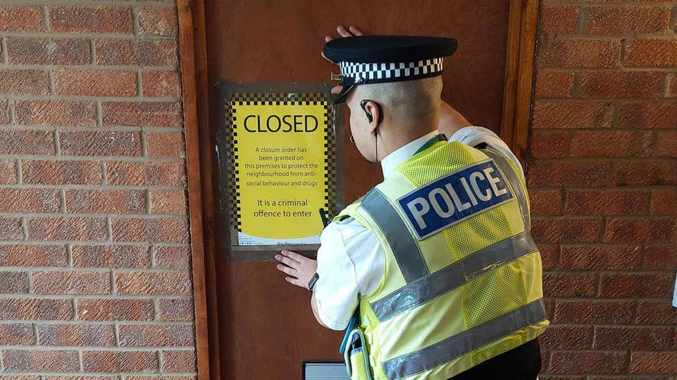 Police officer putting a sign on a door