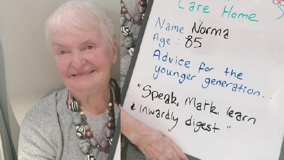 Norma wears a chunky necklace as she looks at the camera with the whiteboard on the other side