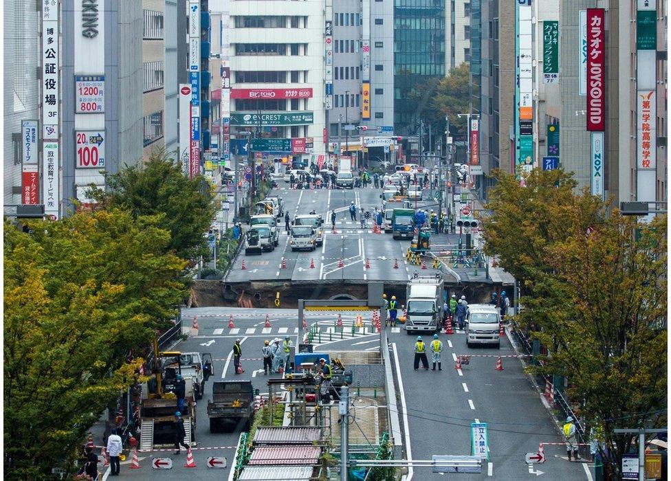 A huge sinkhole on a main street, viewed from a distance, near Hakata station in Fukuoka, Japan, 8 November 2016