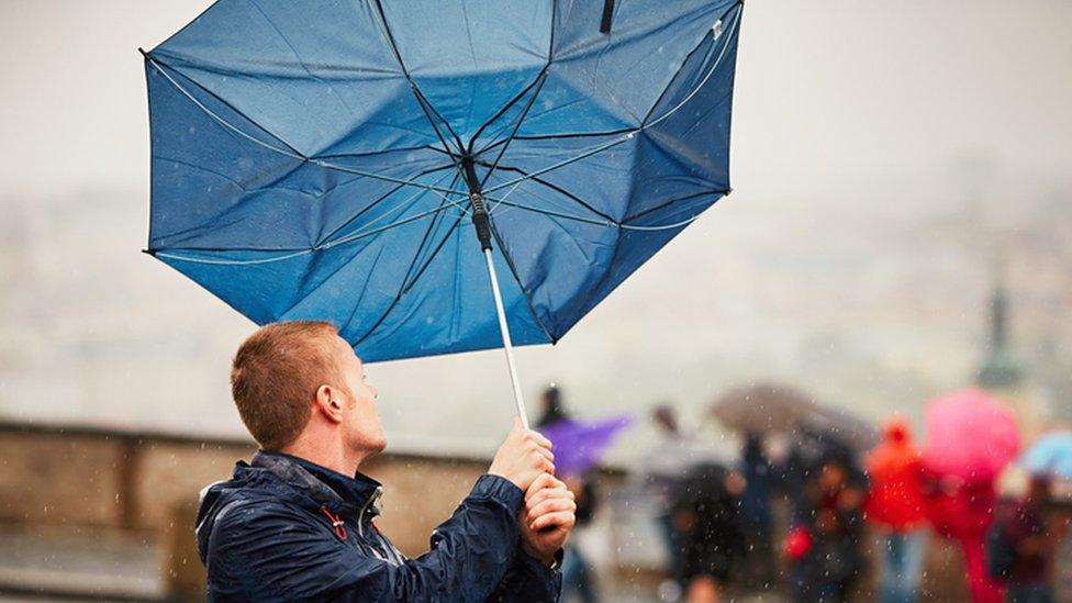 A man struggles with an umbrella in the wind