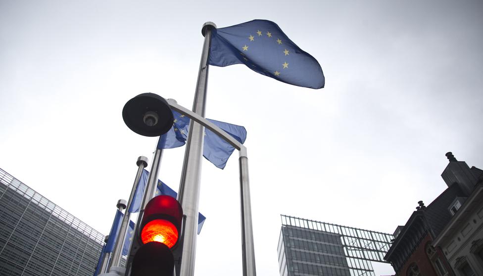 A red light flashes in front of an EU flag in front of EU headquarters in Brussels on Friday, June 24, 2016