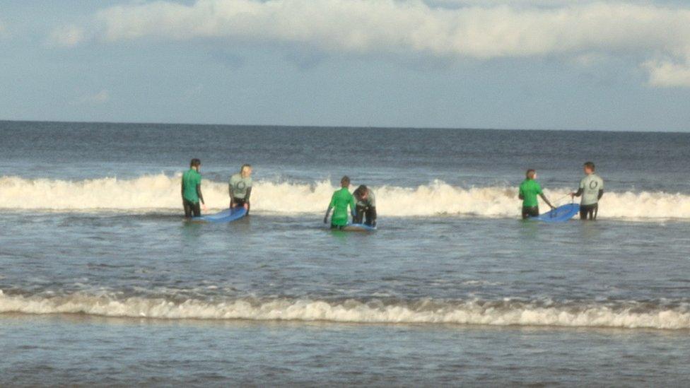 surfing students with their mentors in the sea