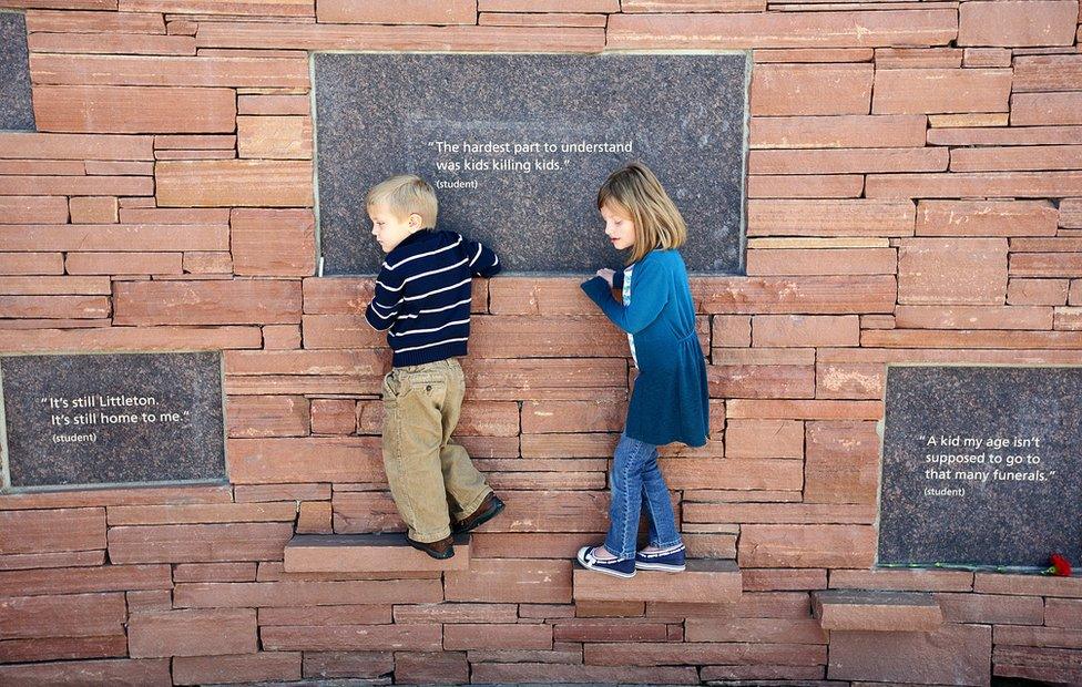 Two children play at the memorial to the Columbine victims, in front of the words: 'The hardest part to understand is kids killing kids'