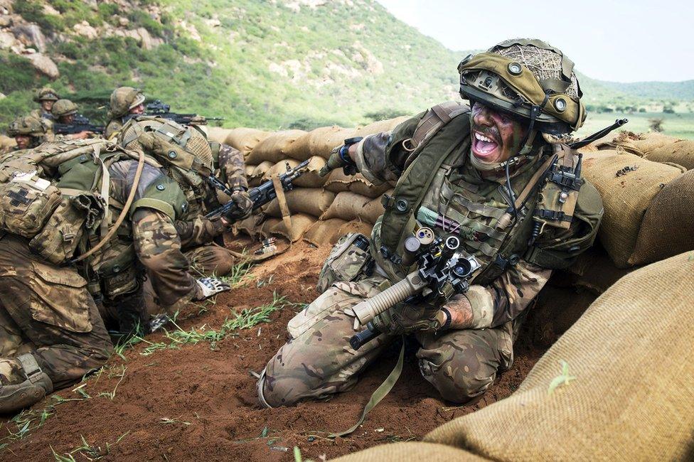 A soldier shouting, surrounded by sandbags