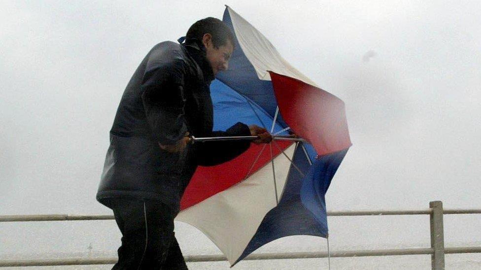 Man struggling to hold an umbrella up in heavy rain