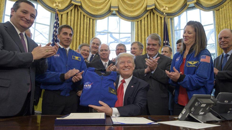 In this handout provided by the National Aeronautics and Space Administration (NASA), President Donald Trump, centre, holds a NASA flight jacket presented to him