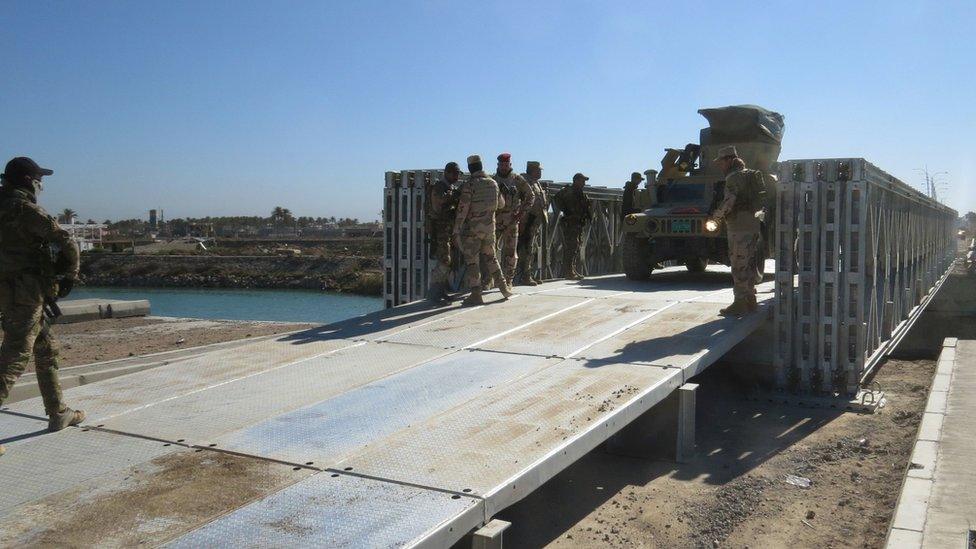 Iraqi government forces cross a temporary bridge in the al-Hamidiya area, north of Ramadi, on 17 February 2016