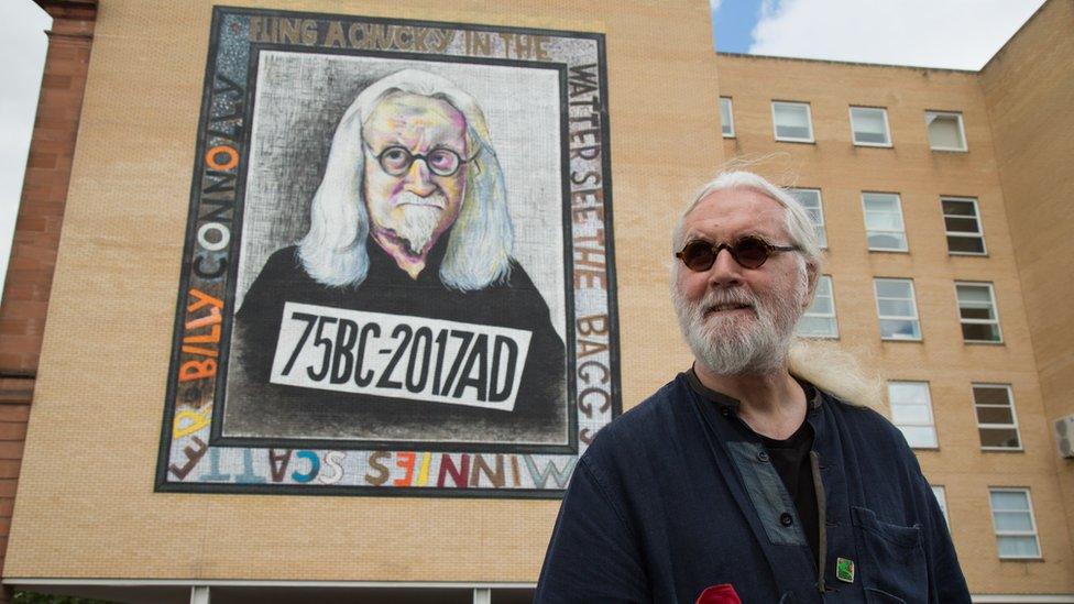 Billy Connolly next to one of his murals