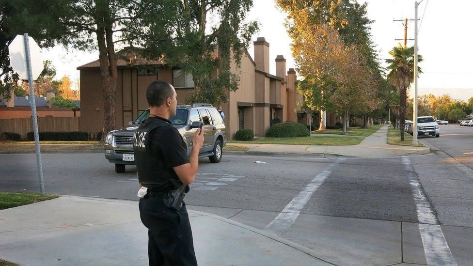 A police officer surveys a row of homes in Redlands, Calif., Wednesday, Dec. 2, 2015,