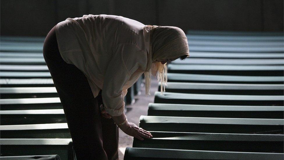 Relative of some of the Srebrenica massacre victims touches one of the 610 coffins containing the remains of family members at the Srebrenica Memorial site on 9 July 2005