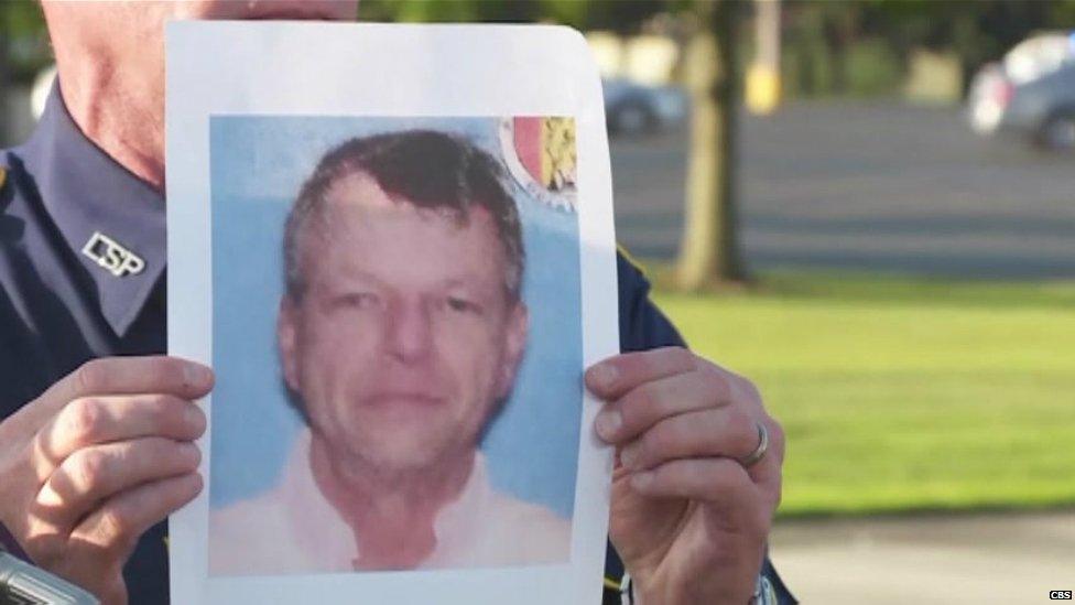 A police officer holds an image of John Houser at a news conference in Lafayette. Louisiana - 24 July 2015