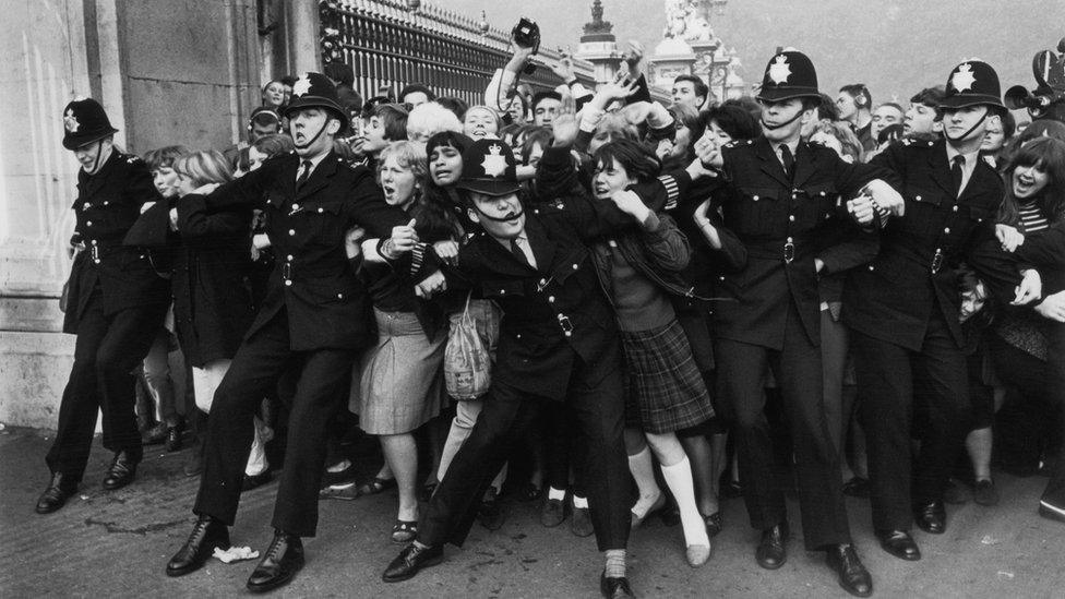 Police officers holding back fans