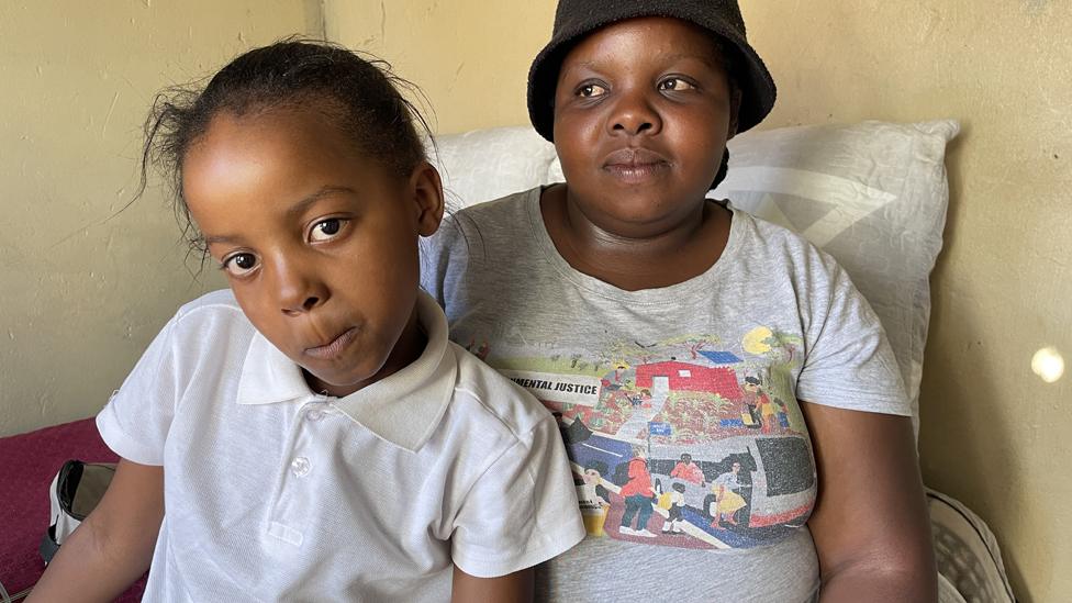 A mother and her daughter sitting on a bed