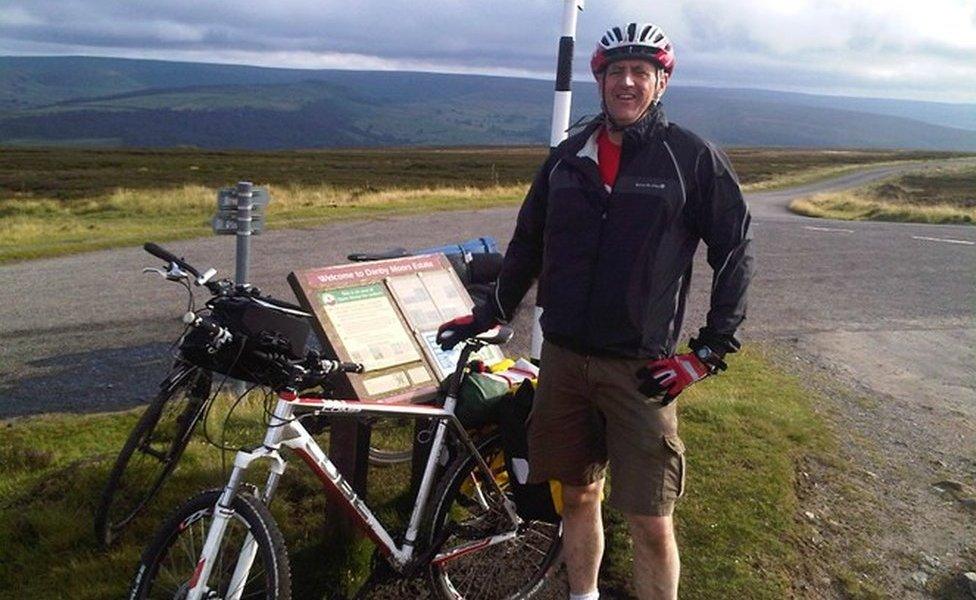 David Collings standing beside his bike in the countryside