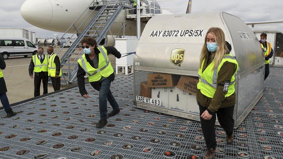 UPS employees move one of two shipping containers containing the first shipments of the Pfizer and BioNTech COVID-19 vaccine a ramp at UPS Worldport in Louisville, Kentucky, on December 13, 2020.