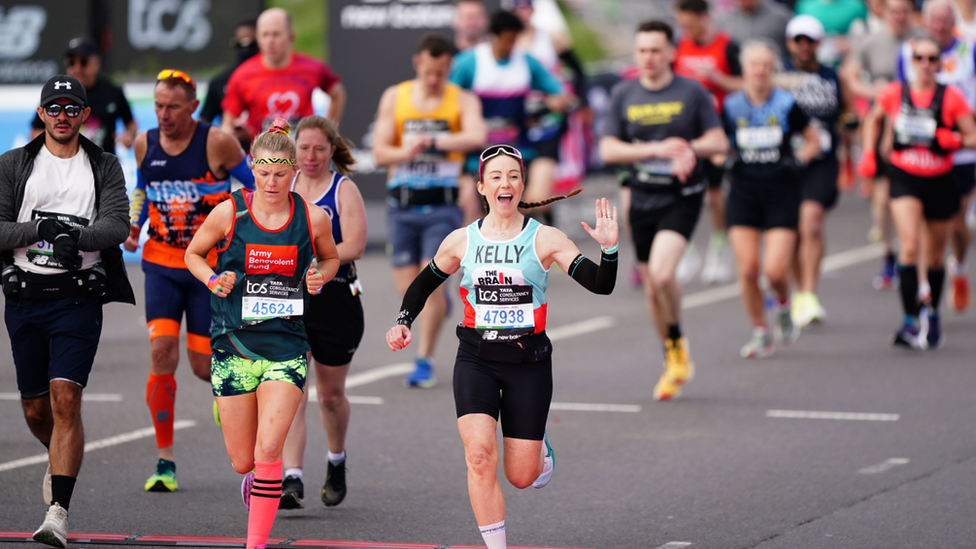 A woman waves at start of race